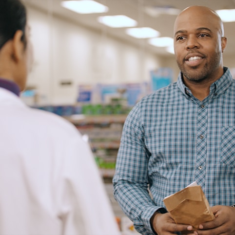 A man at CVS pharmacy counter talking to a pharmacist