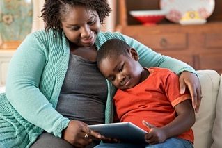 Woman with son on couch looking at tablet
