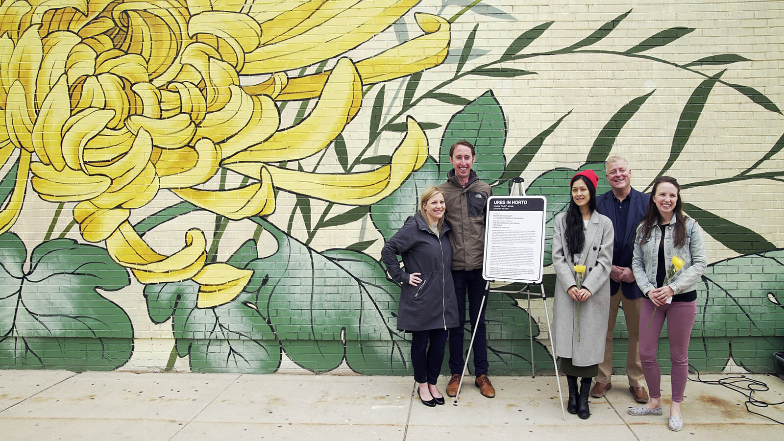 People standing in front of a flower mural.
