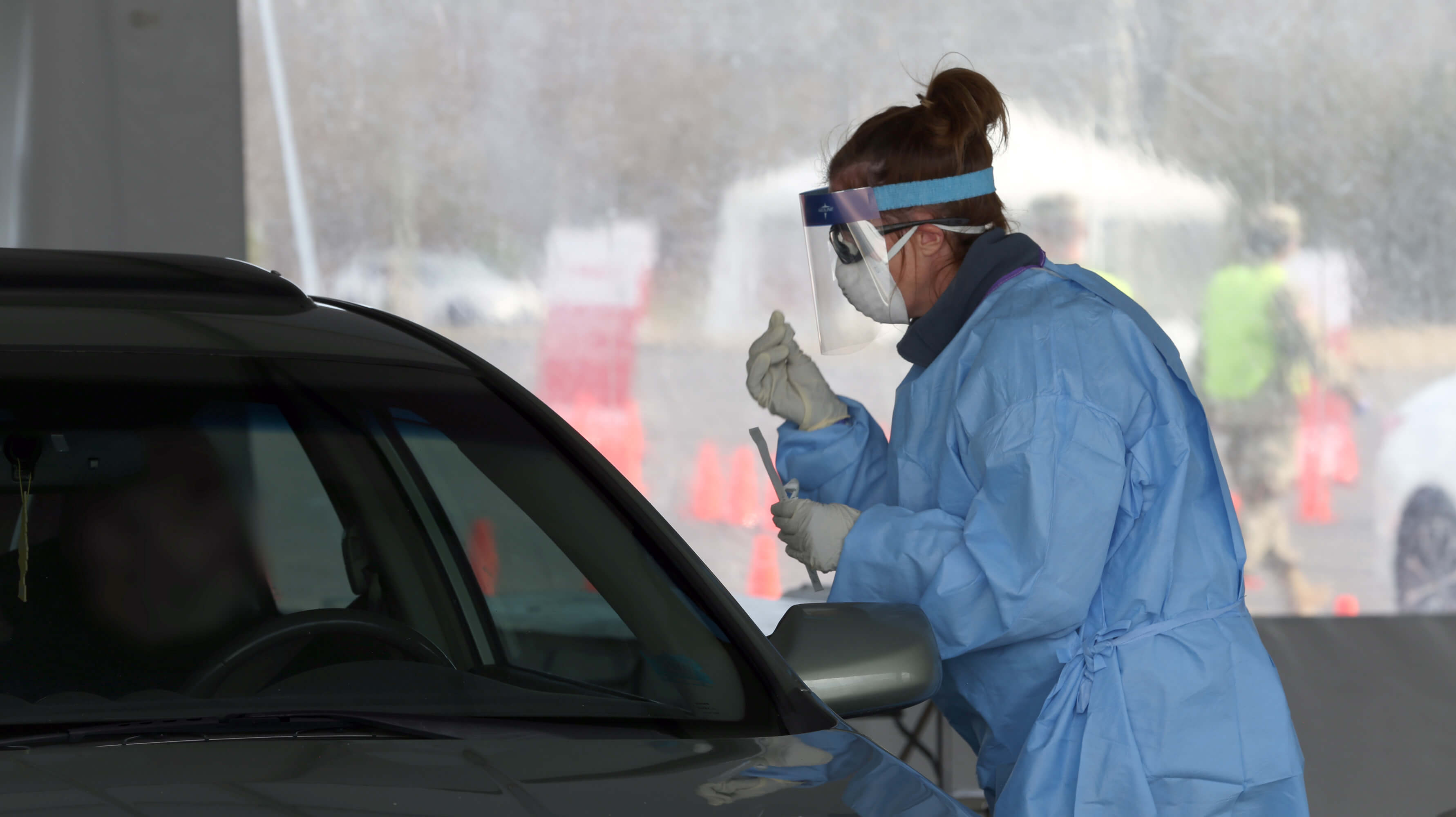 A medical professional examines a swab taken from a patient at a COVID-19 rapid testing drive-through site.