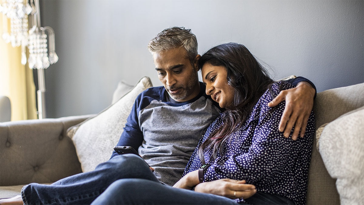 A couple sitting on a sofa looking at a mobile phone