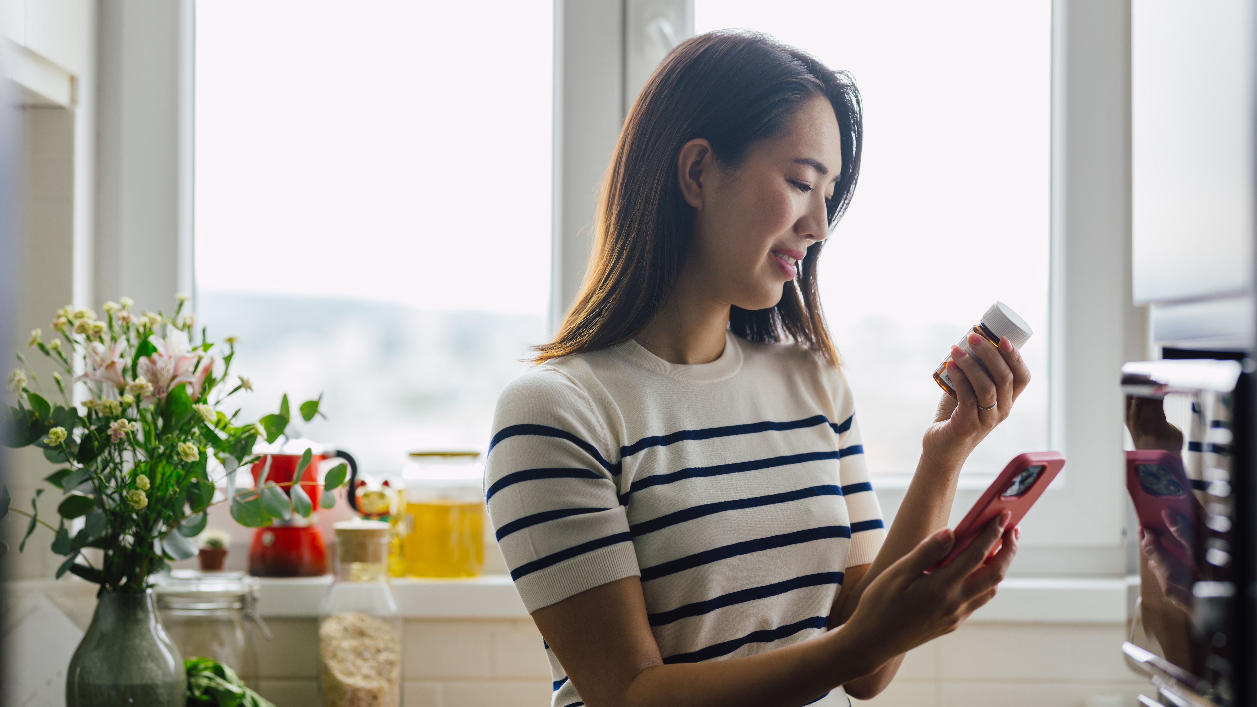 Woman looking at prescription bottle and digital app on phone